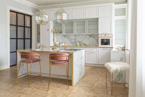 a close view of the white stylish kitchen with a cooking island in the luxurious interior of a modern apartment in light colors with stylish furniture.