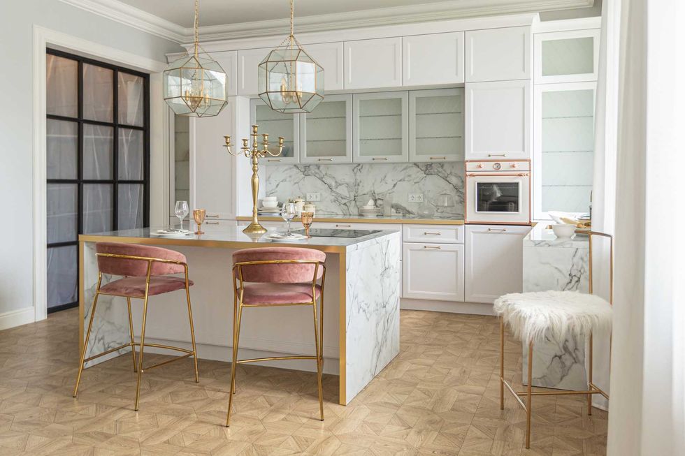a close view of the white stylish kitchen with a cooking island in the luxurious interior of a modern apartment in light colors with stylish furniture.