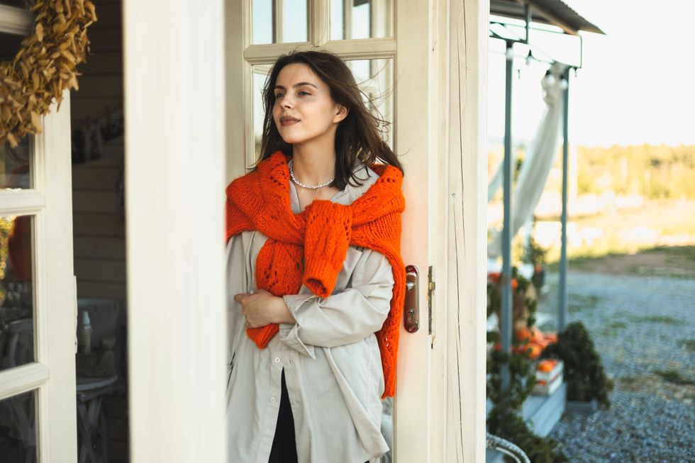 A girl is holding a pumpkin on the porch of her house. decorating houses for Halloween. Autumn home decor. Autumn mood