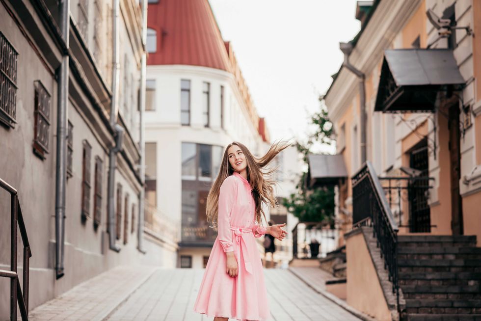 A young, beautiful girl in a pink dress walks through the beautiful streets in the city. Photo close - up and General plan. Very beautiful portraits of a girl in the city.