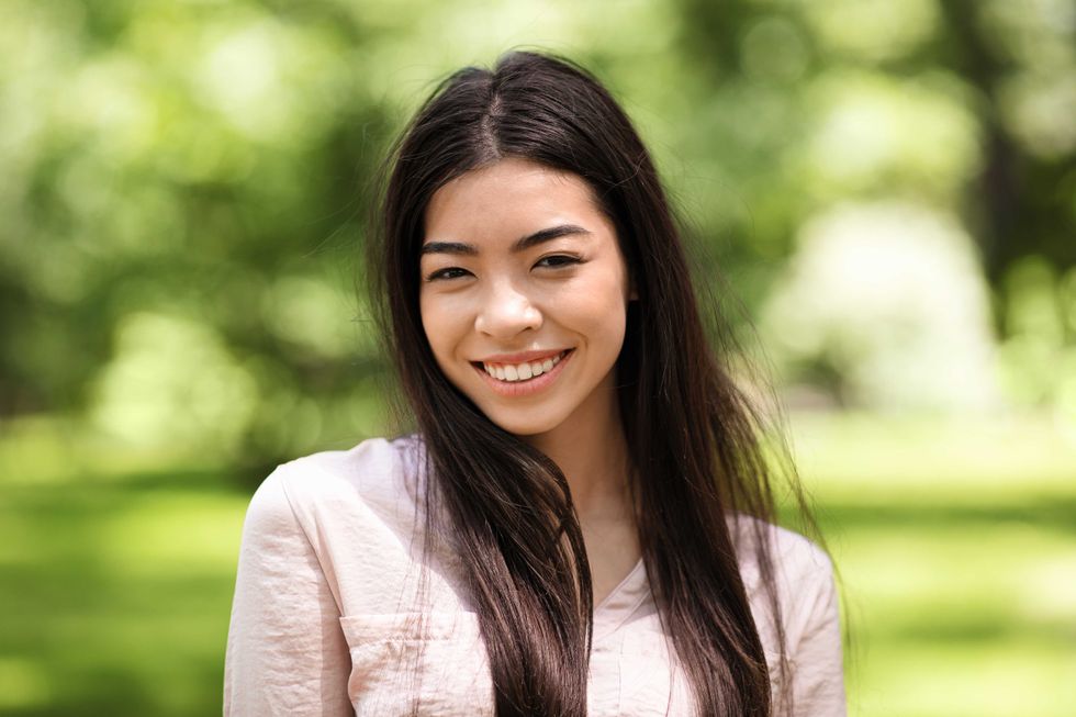 Asian Beauty. Outdoor Portrait Of Smiling Beautiful Korean Girl Posing To Camera In Summer Park, Closeup Shot With Selective Focus And Free Space