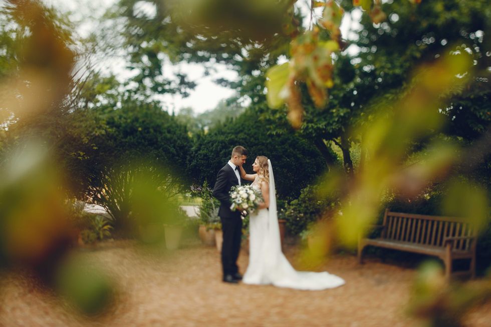 Beautiful bride in a long white dress. Handsome groom in a black suit. Couple in a summer park