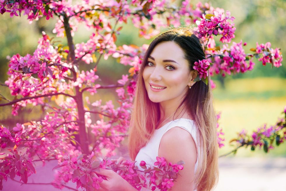 Beautiful girl with color hair Ombre is in blossoming pink tree in the spring and . Beautiful eyes and a pretty face.