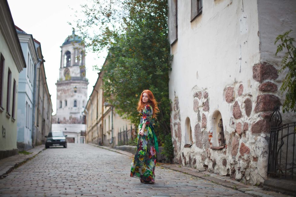 beautiful red-haired girl walks along the old streets of Vyborg