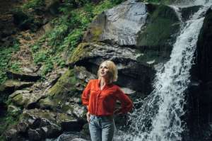 beautiful woman posing near waterfall on forest background.