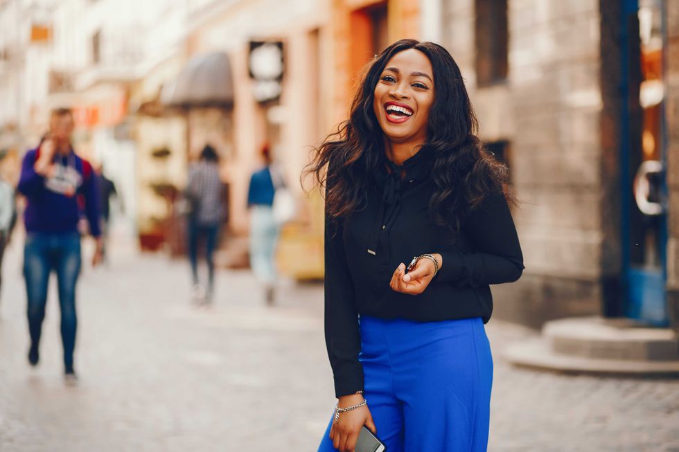 Elegant black woman standing in a summer city. Businesswoman in a blue pants