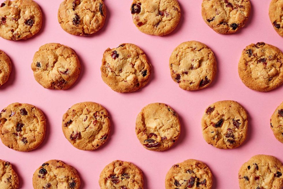 Fresh cookies with cranberries and white chocolate pattern on pink background