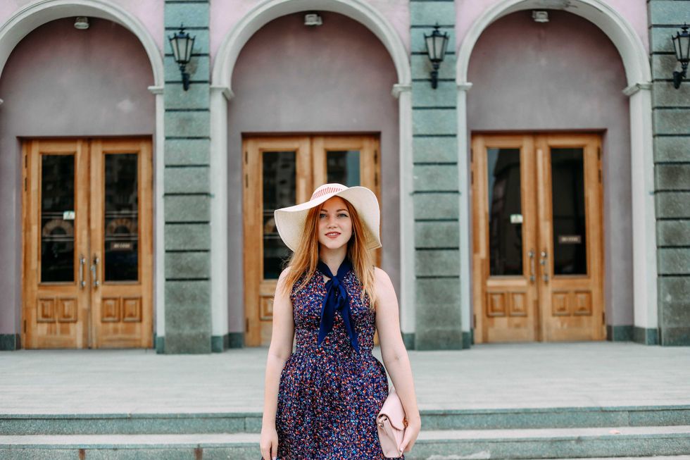 girl on a city street with a hat and handbag