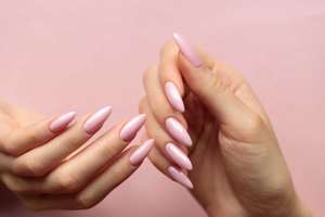 Girl's hands with a beautiful pink manicure on a light pink background