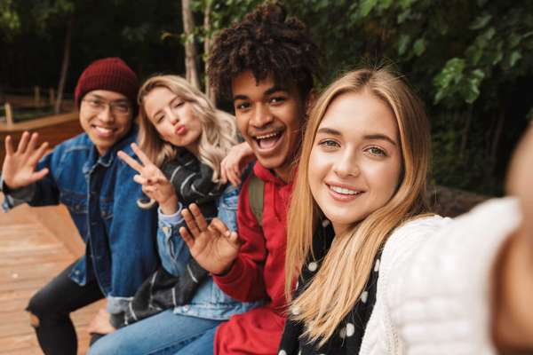 Group if cheerful multiethnic friends teenagers spending fun time together outdoors, taking a selfie