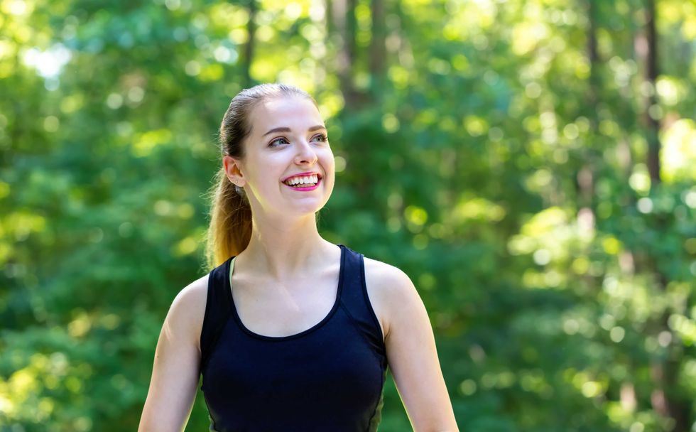 Happy healthy fit woman on a bright summer day in the forest