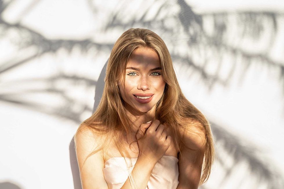 Lovely beautiful young blonde woman with natural freckles smiling to the camera. Natural shadows. A lot of copy space.