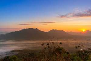 Majestic Sunrise over Misty Mountain Valley with Golden Light,A breathtaking panoramic view of a mountain range at sunrise, featuring a thick layer of morning mist (sea of fog) covering the valley.