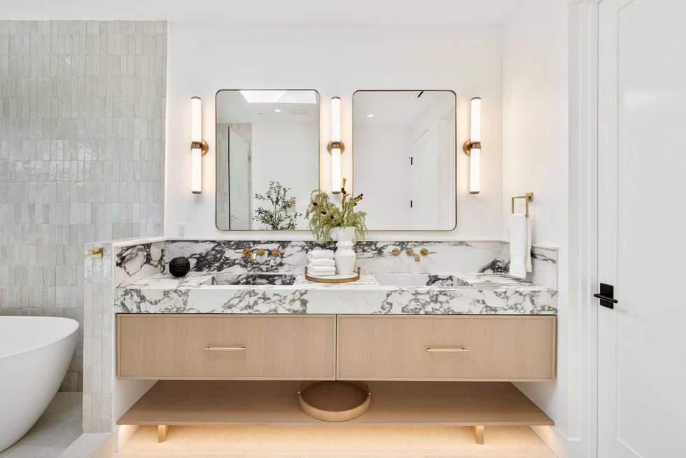 Modern bathroom with marble countertop and dual mirrors.