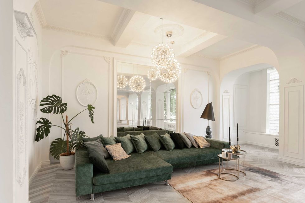 Morning in luxurious light interior in the Baroque style. Bright and clean interior design of a luxury living room with parquet wood floors, fireplace, sofa and flowers. Stucco on walls.