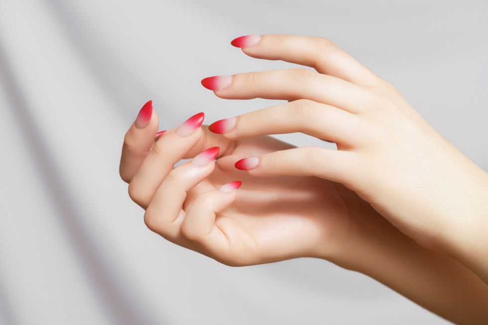 Nail design, manicure with gel polish. Women's hands with a gradient red manicure. Beautiful woman's hands with ombre gradient nail design. Manicure, pedicure beauty salon concept. High quality photo