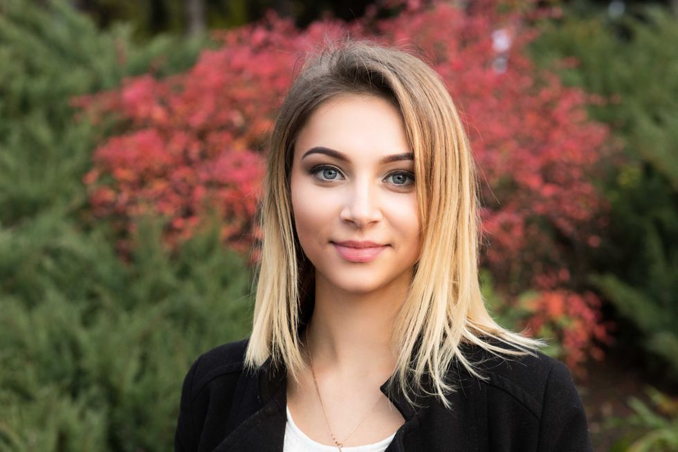 Portrait closeup of nice young woman against background of summer early autumn nature park green red leaves beautiful woman