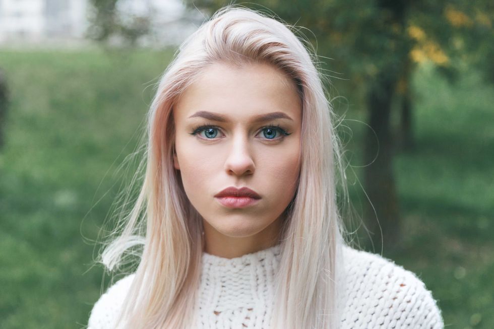 Portrait of a beautiful serious blonde girl in a white knitted sweater