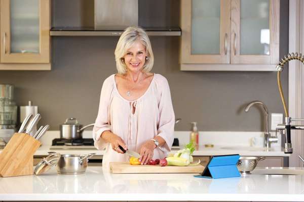 Portrait of older woman in kitchen cutting vegetables