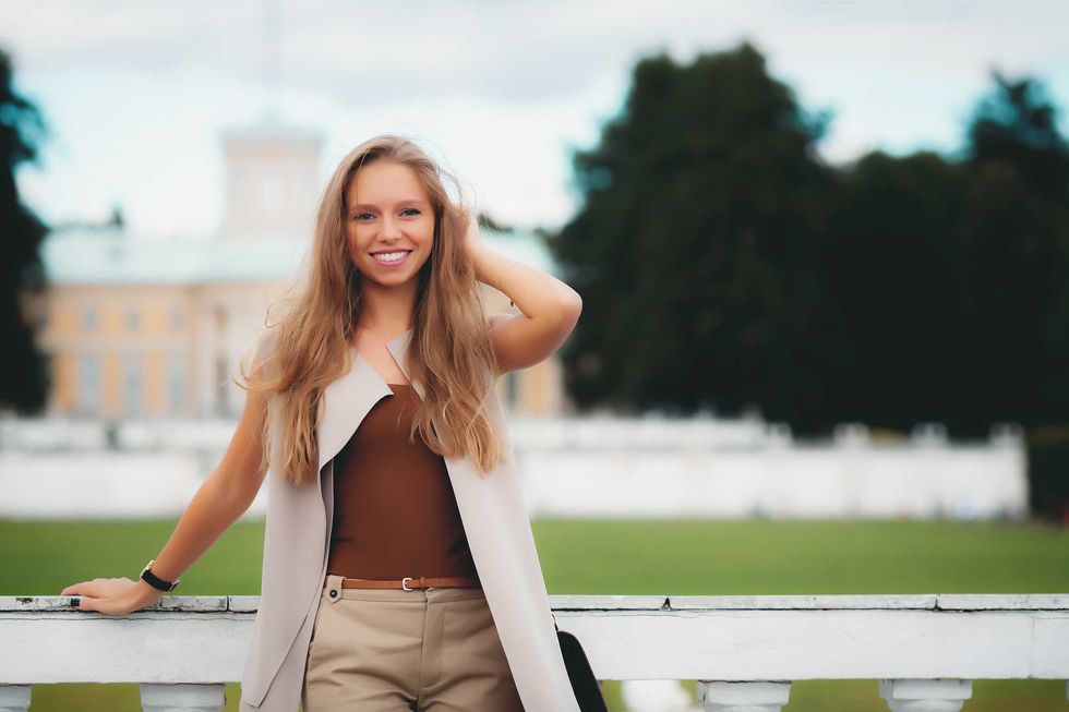 portrait of young smiling attractive caucasian woman in stylish summer outfit in the park