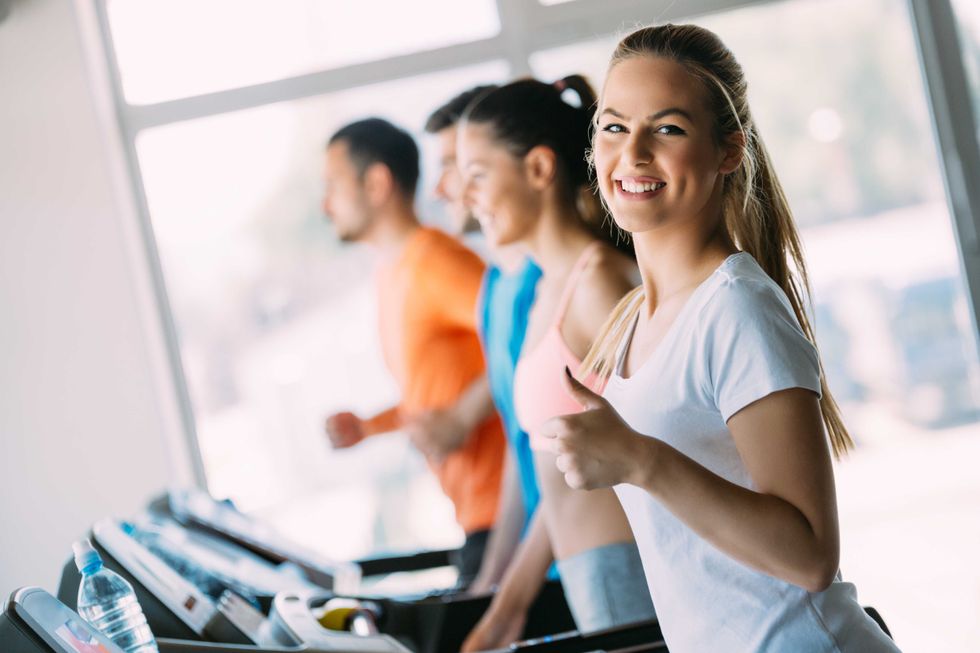 Pretty girl working out in a treadmill at the gym and smiling