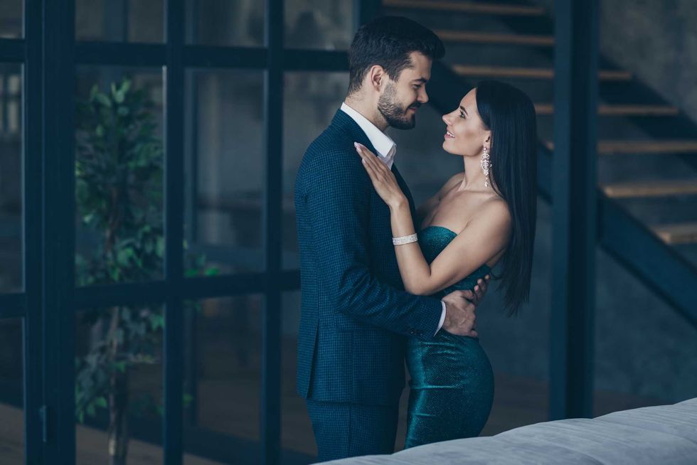Profile photo of two famous trendy people couple rich guy and lady standing, close looking eyes happily smiling romance date wear classy formalwear suit dress loft indoors