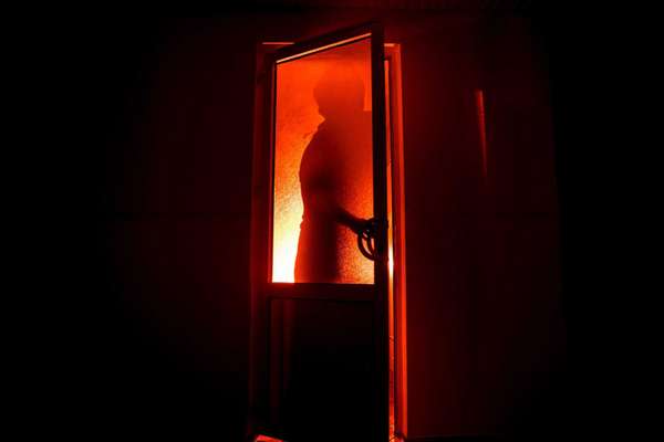 Silhouette of an unknown shadow figure on a door through a closed glass door. The silhouette of a human in front of a window at night. Scary scene halloween concept of blurred silhouette of maniac.