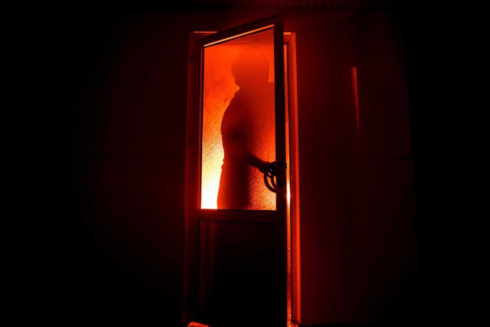 Silhouette of an unknown shadow figure on a door through a closed glass door. The silhouette of a human in front of a window at night. Scary scene halloween concept of blurred silhouette of maniac.