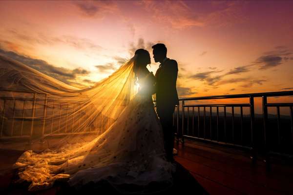 silhouette of wedding Couple in love kissing and holding hand together during sunset with evening sky background
