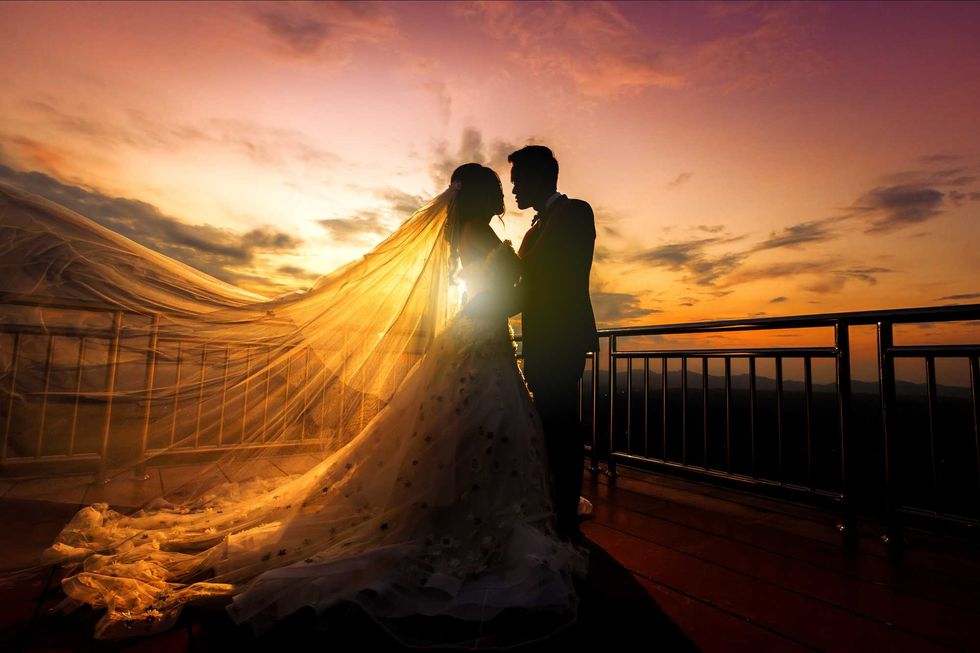 silhouette of wedding Couple in love kissing and holding hand together during sunset with evening sky background