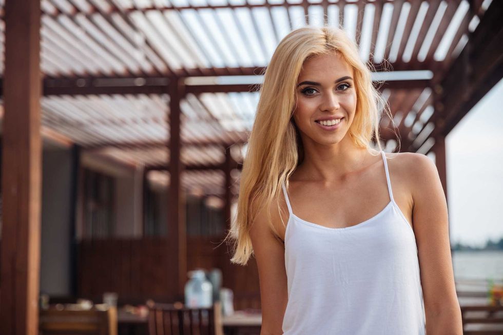 Smiling beautiful young woman with long blonde hair standing outdoors