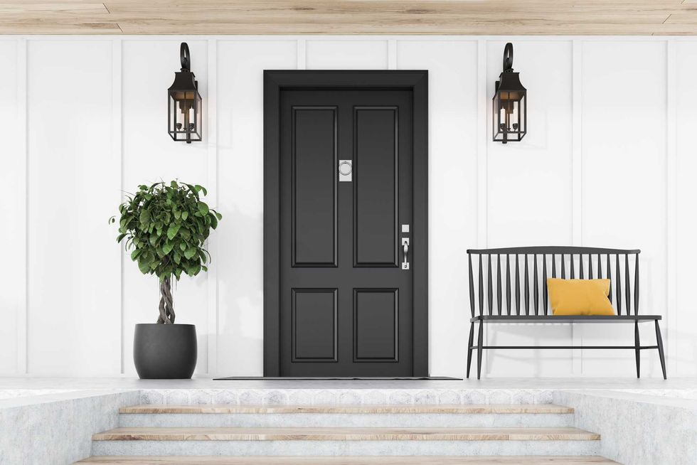 Stylish black front door of modern house with white walls, door mat, tree in pot, black bench, stairs and lamps. 3d rendering