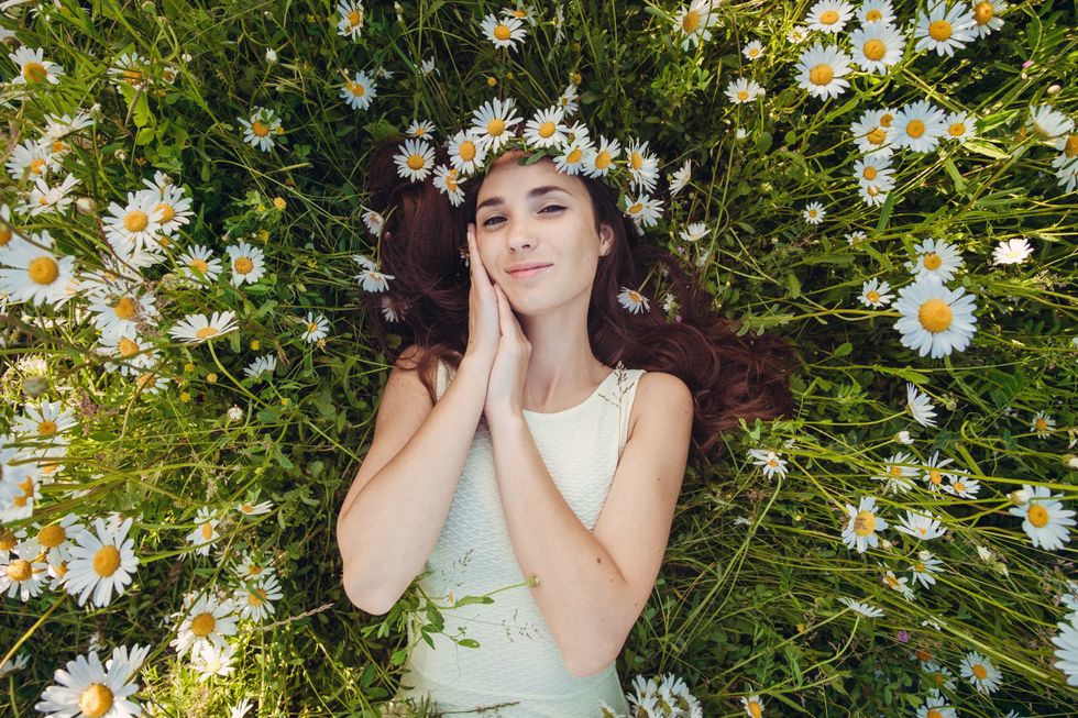 The beautiful woman lies in the field of chamomiles. . Carefree happy brunette woman with healthy long hair having fun outdoor in nature. harmony concept