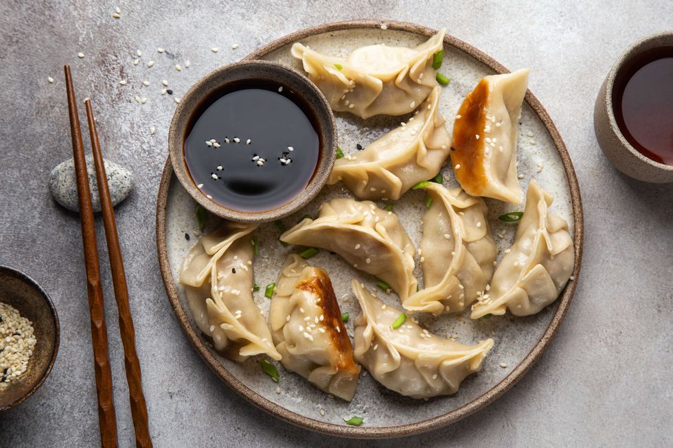Traditional japaneese gyoza dumplings with meat and mushrooms on ceramic plate, top view