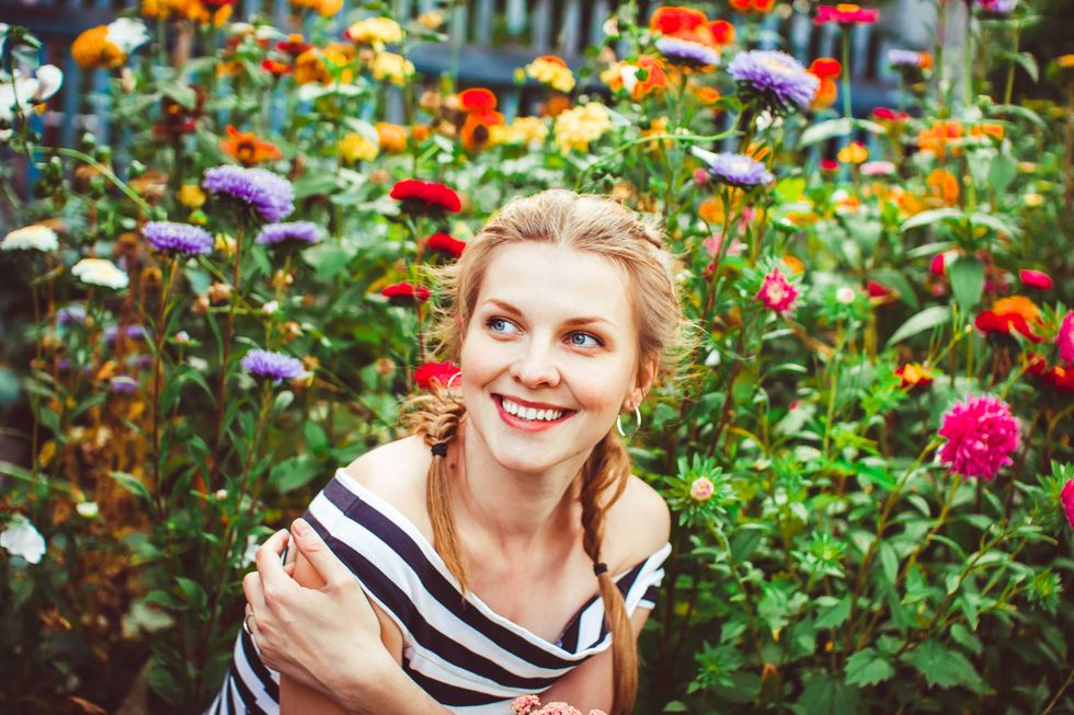 Woman in a summer garden in a dress among flowers