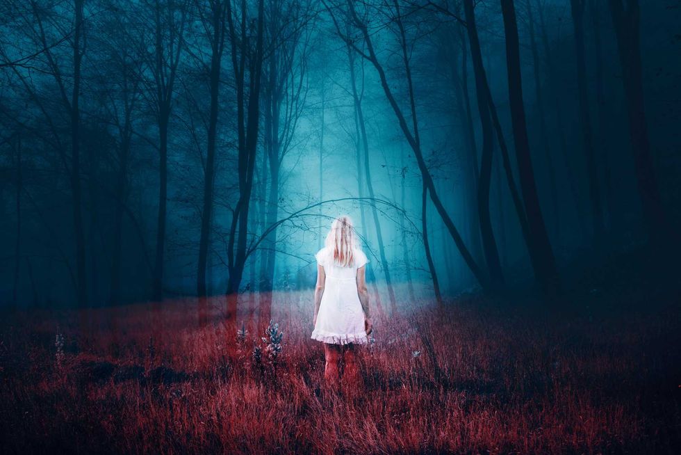 Woman standing in foggy mysterious fantasy forest with grass on the floor. The image with the effect of double exposure.
