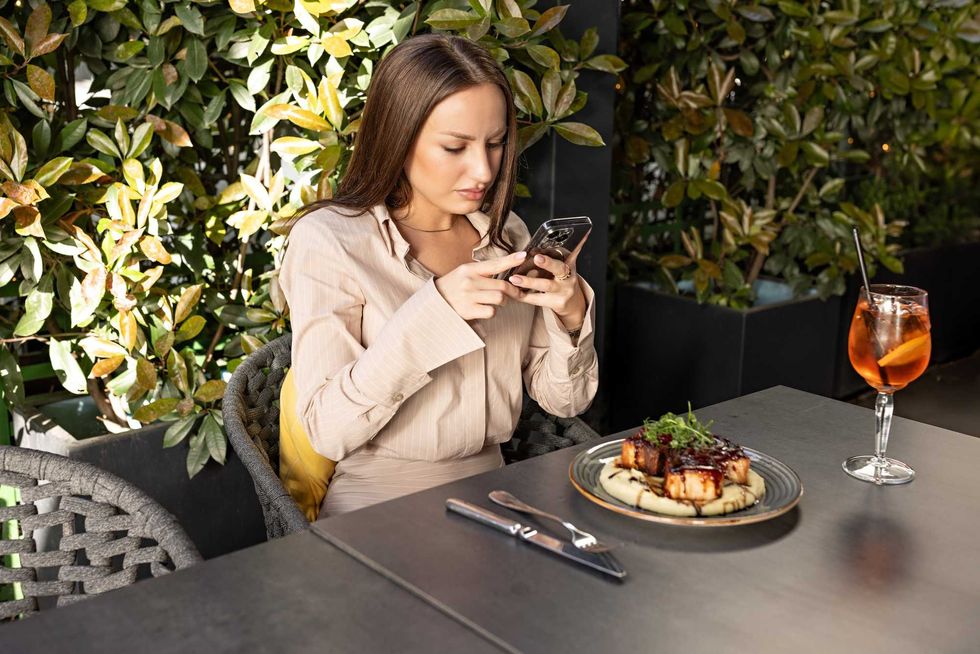 Woman taking picture of her plate at outdoor restaurant