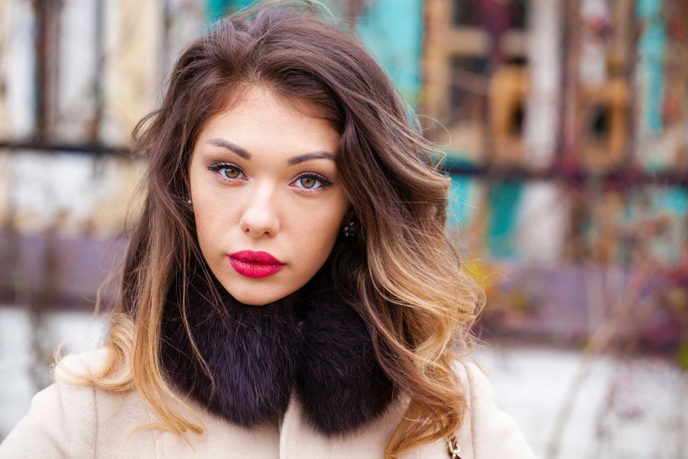 Young brunette woman in gray woolen coat on background autumn park