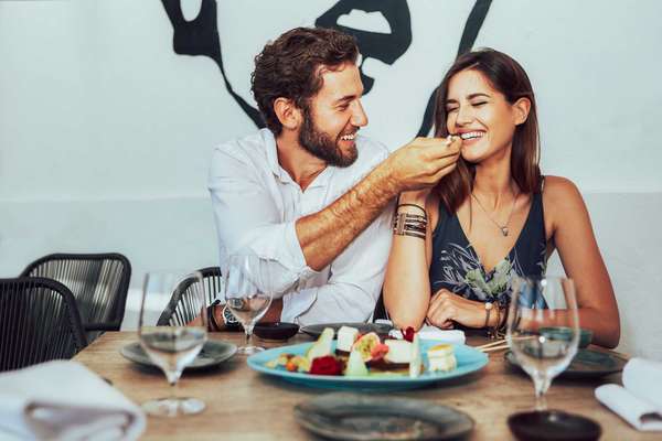 young couple sitting in a cafe and feed each other the juicy cakes