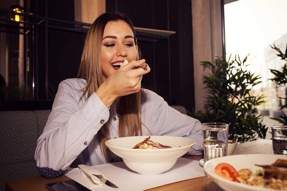 Young woman eating tasty food in a restaurant, having her lunch break. Close up